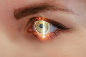 Gros plan sur oeil vert d'une femme, avec un trait lumineux traversant l'oeil à la verticale