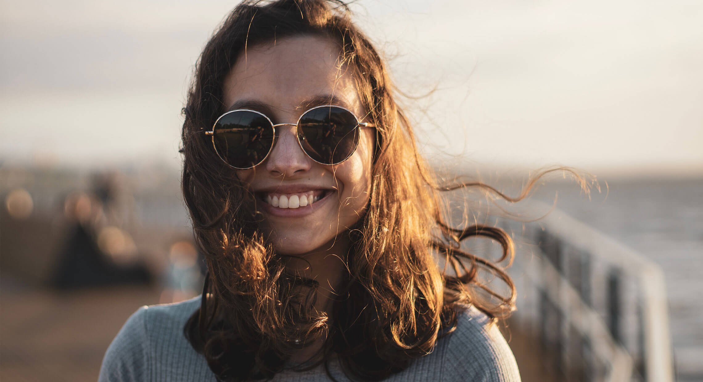 Jeune femme avec des lunettes solaires qui sourit sur un quai
