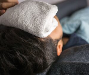 Homme avec compresse humide sur les yeux